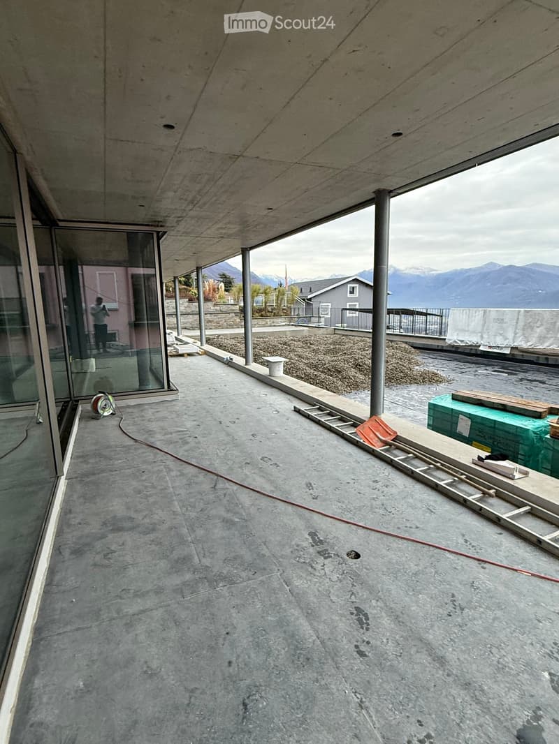 concrete floor, glass walls, ladders, construction materials, lake and mountain view