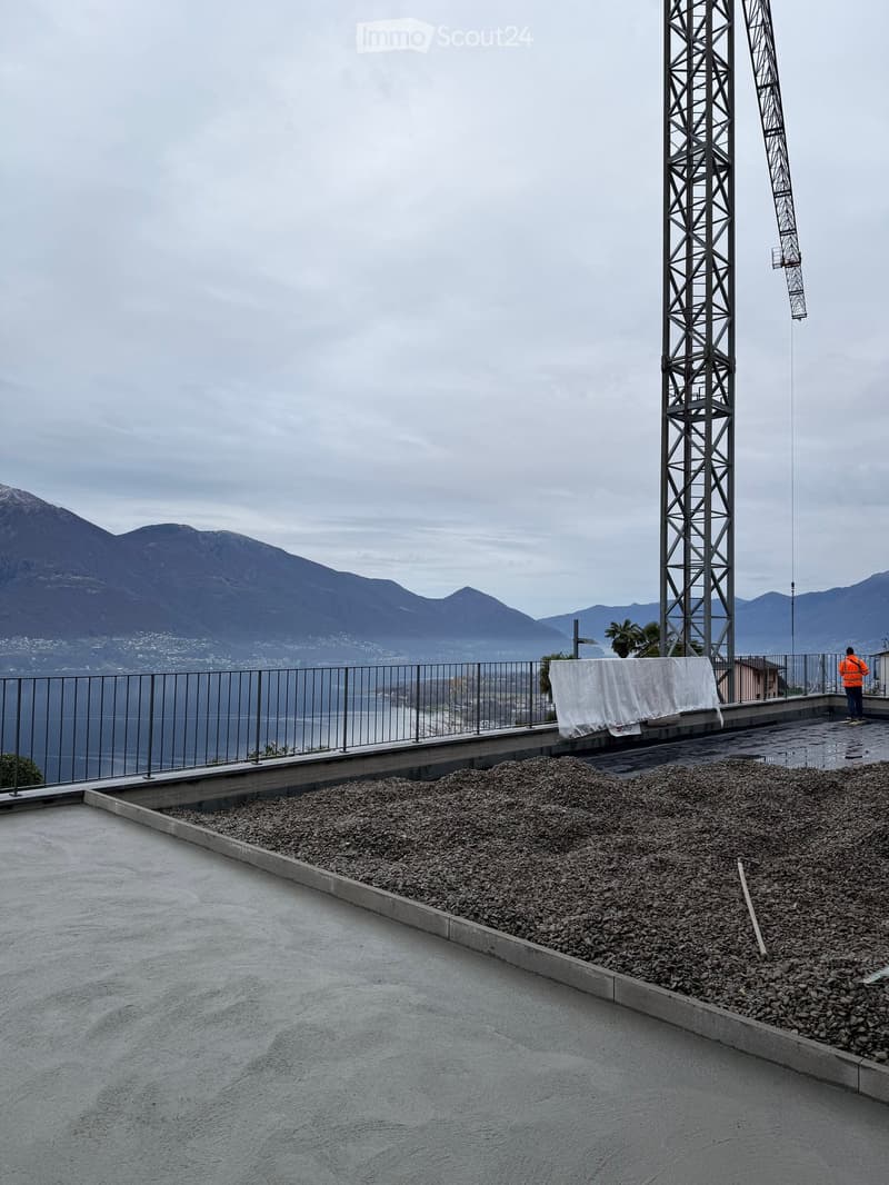 roof construction site, crane, gravel, concrete, steel fence, mountains, lake, clear sky