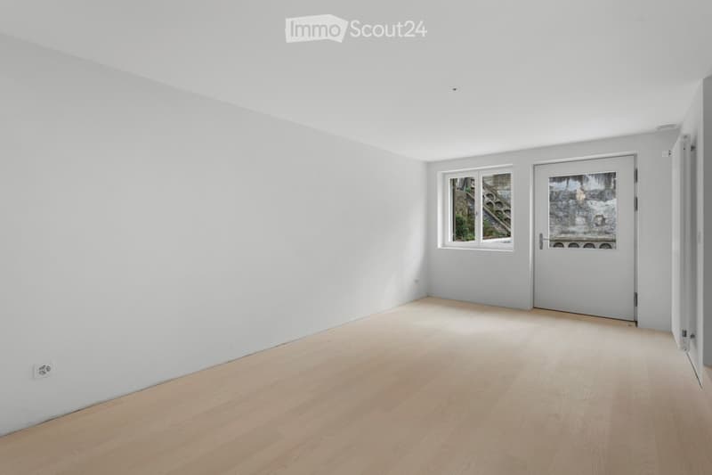 empty room with wooden floors, two windows, power outlet on the wall