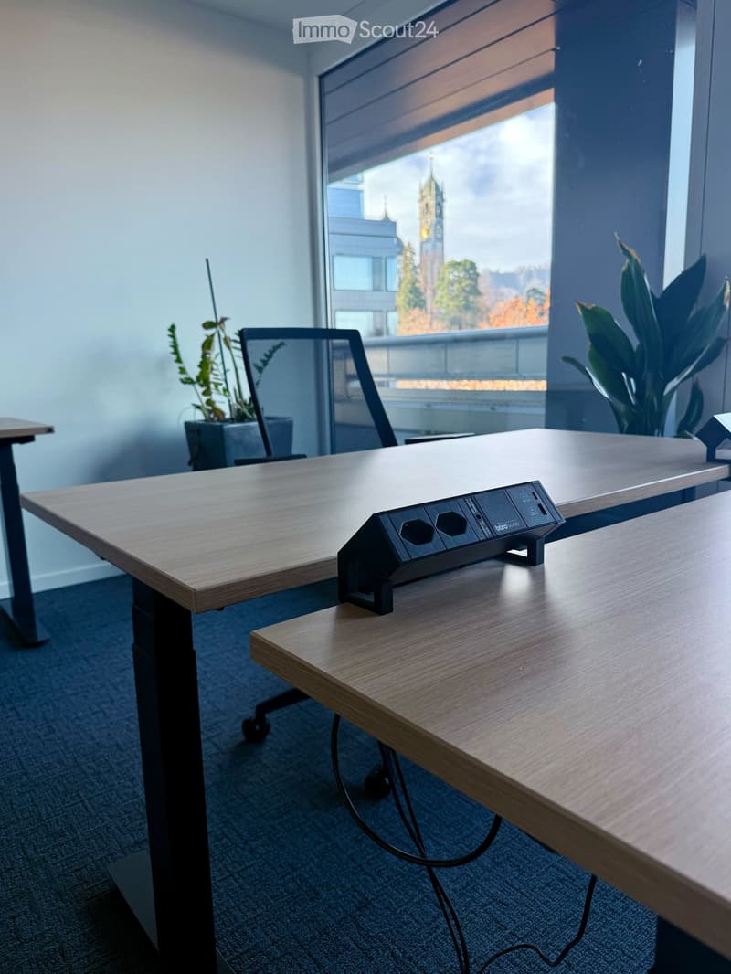 A workspace with desks, a standing desk, office chair, plants, large window with city view