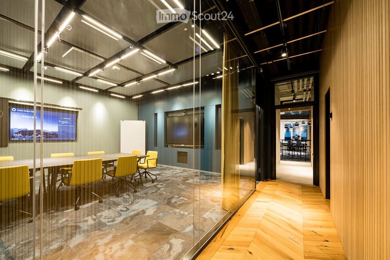 Meeting room with glass wall, wooden floor, yellow chairs, large desk, television, projection screen