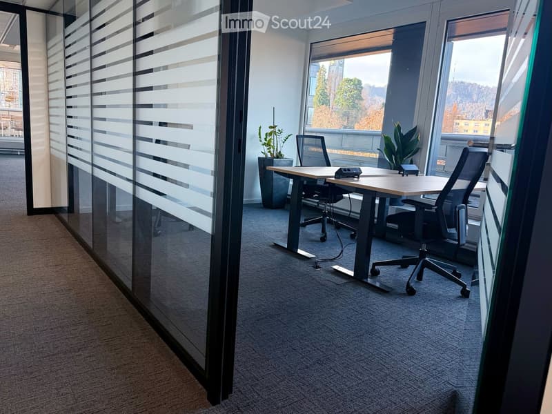 empty office with desks and chairs, two windows overlooking the outside, large glass walls