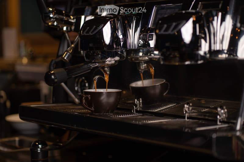 Modern black espresso machine, brewing coffee into two cups, multiple settings and functions.