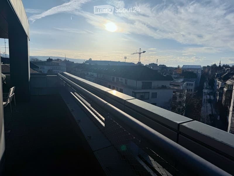 modern balcony with railing, glass railing, chair, view of the city, brick floor