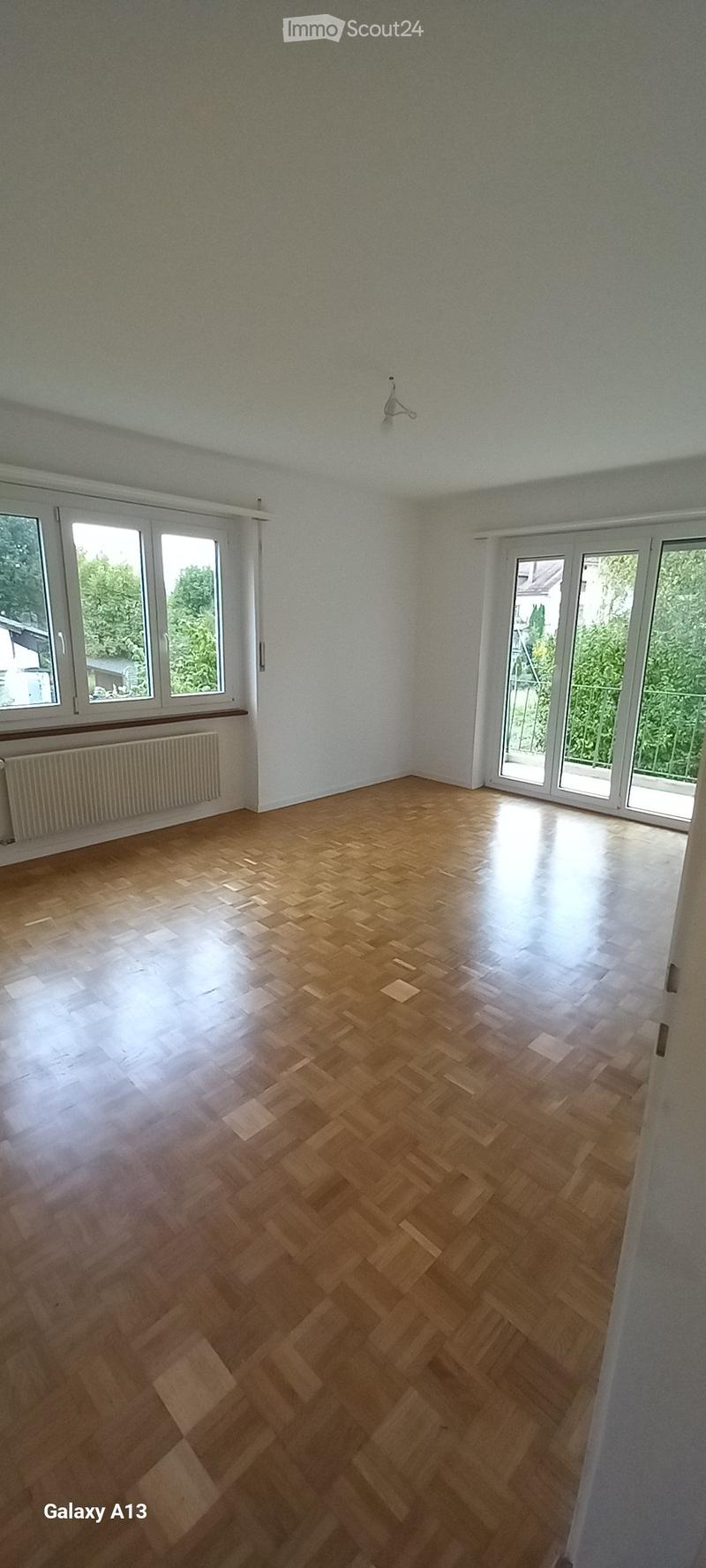 hardwood floor, large windows, glass sliding doors leading to balcony, radiator, no furniture
