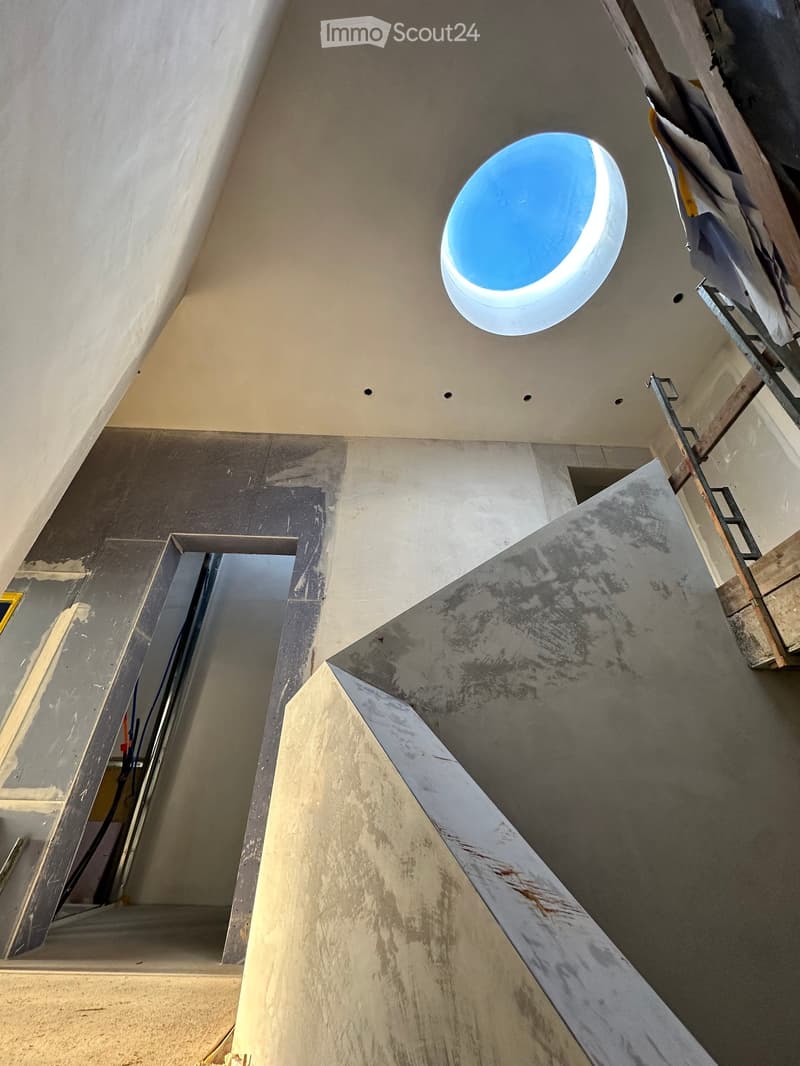 unfinished building interior, sky-dome window, concrete walls, exposed steel bars, no flooring
