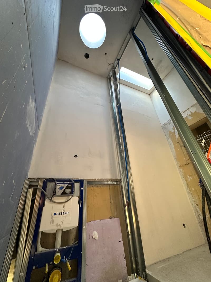 Interior staircase with ceiling opening, unfinished wall with visible wiring, raised ground floor