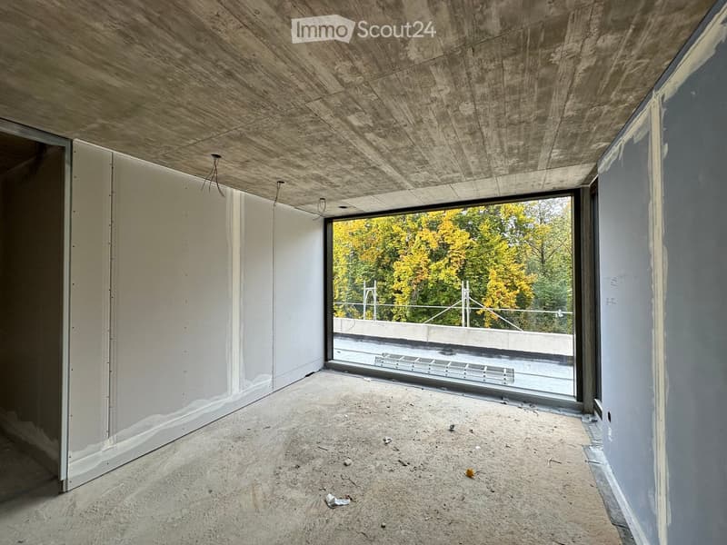 empty room with unfinished walls, concrete ceiling, large glass wall with view to terrace and trees
