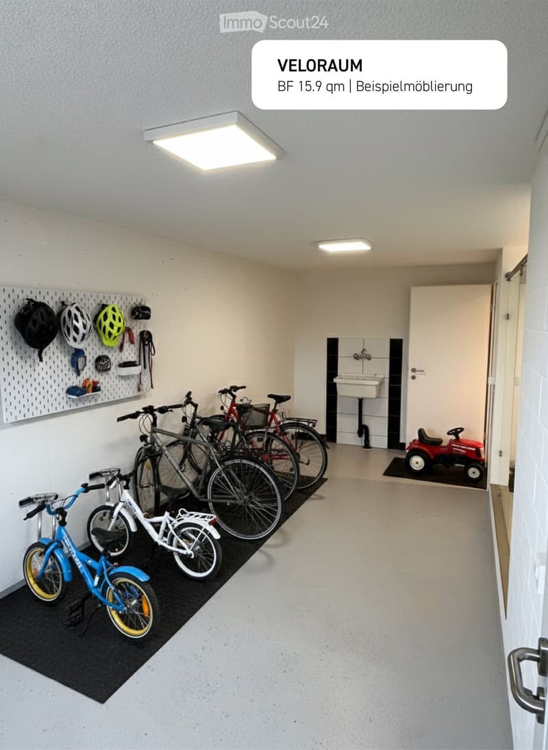 Garage with several bicycles parked on the floor and a toy car on a black mat, helmet and helmet holder hanging on the wall, a door, and a small sink attached to the wall