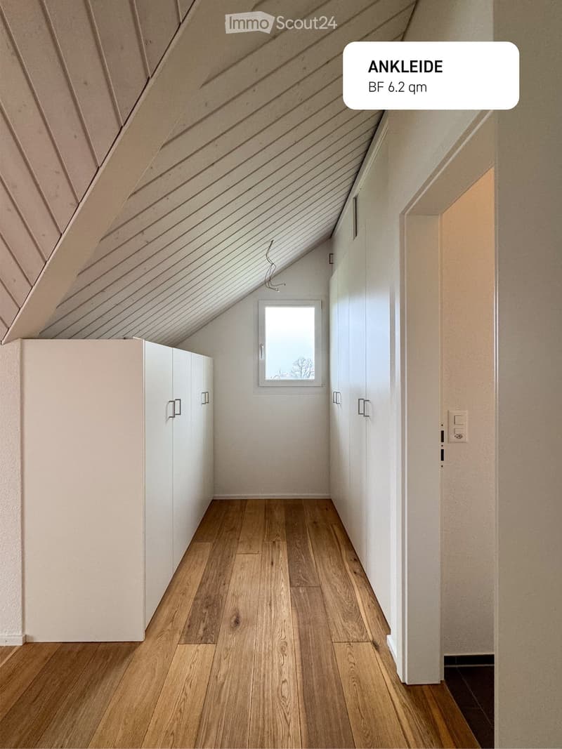 attic room, white walls, wooden flooring, built-in cabinets, small window