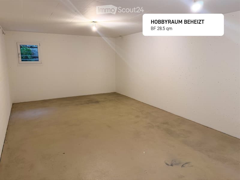 Empty room, concrete floor, a small window, and dim lighting from the ceiling.