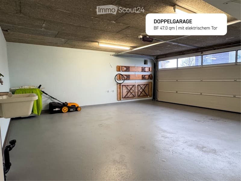 Spacious double garage with electrical doors, a sink, hooks for storage, and two vehicle lights