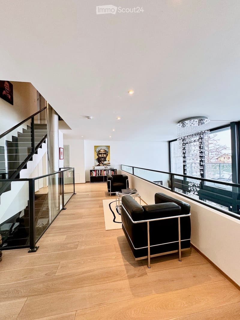 open floor plan, hardwood floor, modern chandelier, glass railing, black leather sofas, glass coffee table, glass staircase