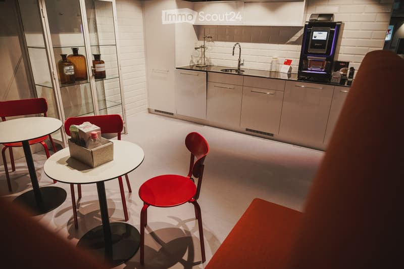 modern kitchen with a table and two red chairs, sink, cabinets, countertop, a shelf with bottles, a bench