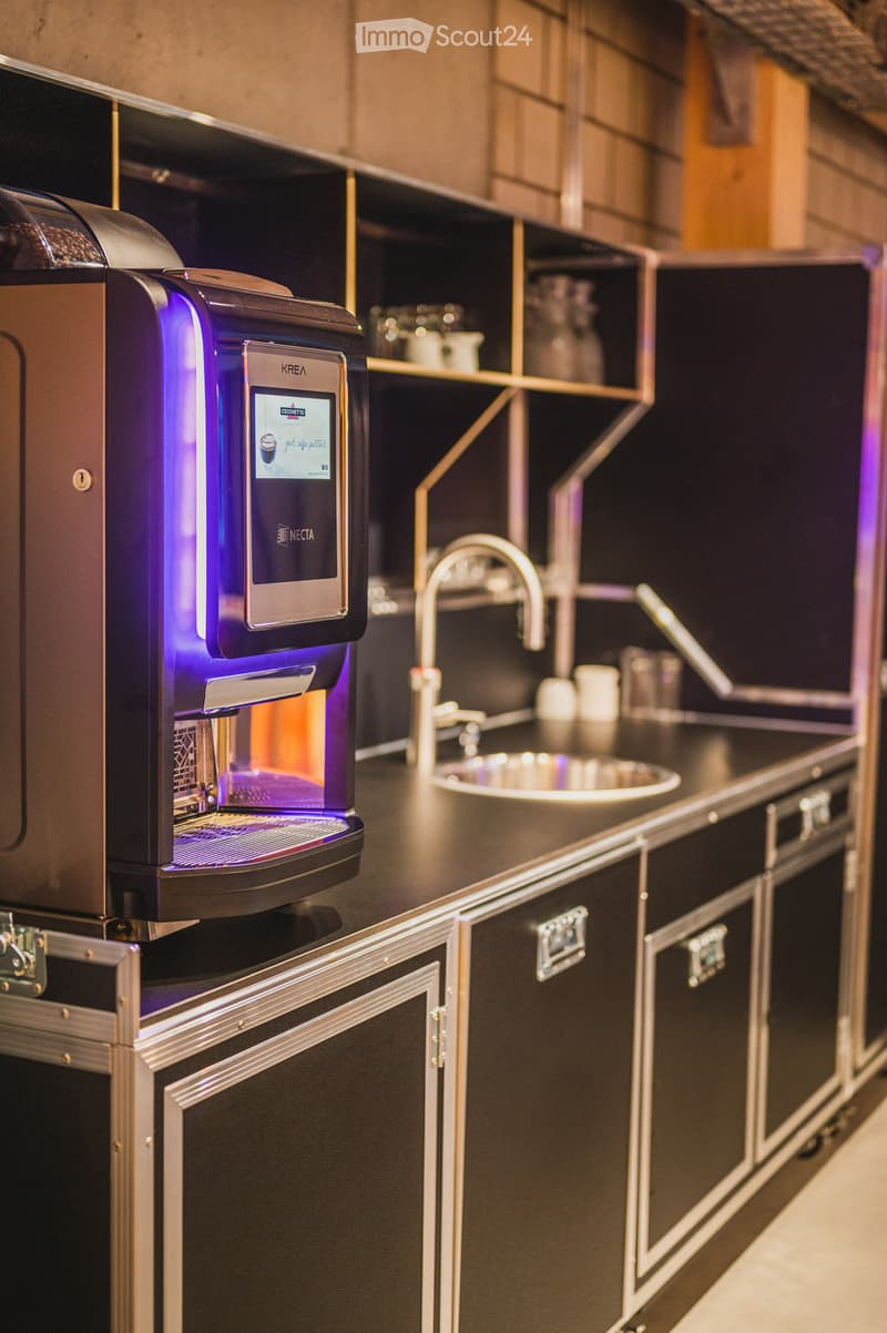Commercial kitchen area, black cabinets, stainless steel sink, large coffee machine, illuminated purple