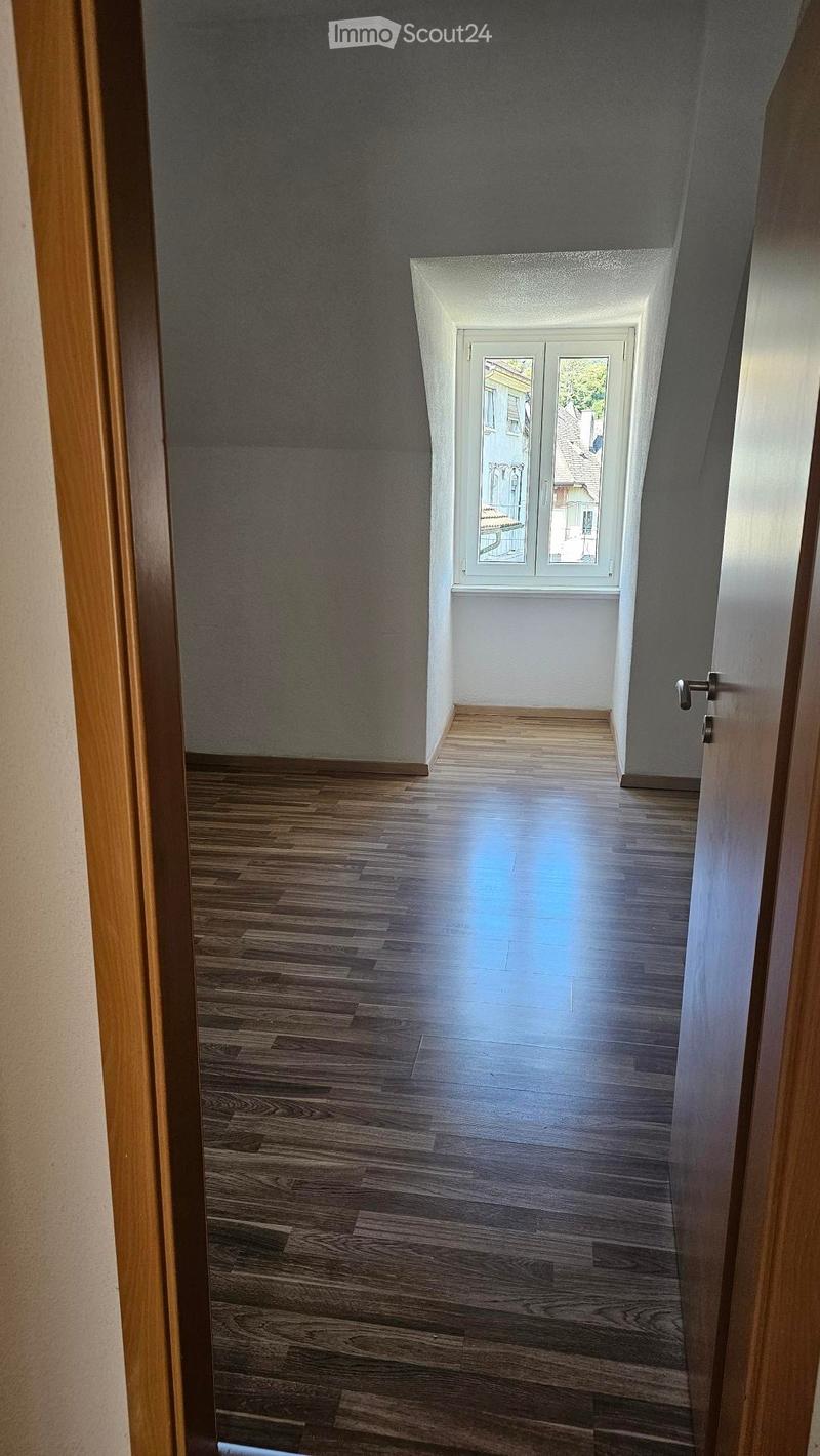 wooden floor, white walls, window with a view of a town