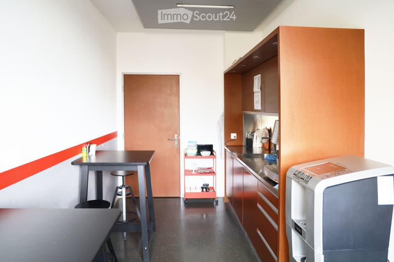 Small kitchen with tables, stools, a door, shelves, a microwave, and a coffee machine