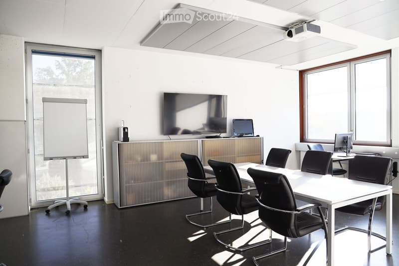 Office conference room with large windows, flat screen TV, projector, whiteboard, and black office chairs.