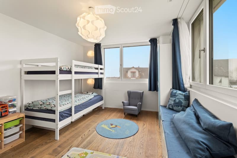 double bunk beds, small armchair, couch, round rug, two storage boxes