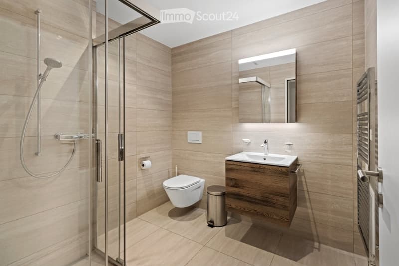 Bathroom with wooden floor, shower, toilet, sink, wooden cabinet, towel warmer, and mirror
