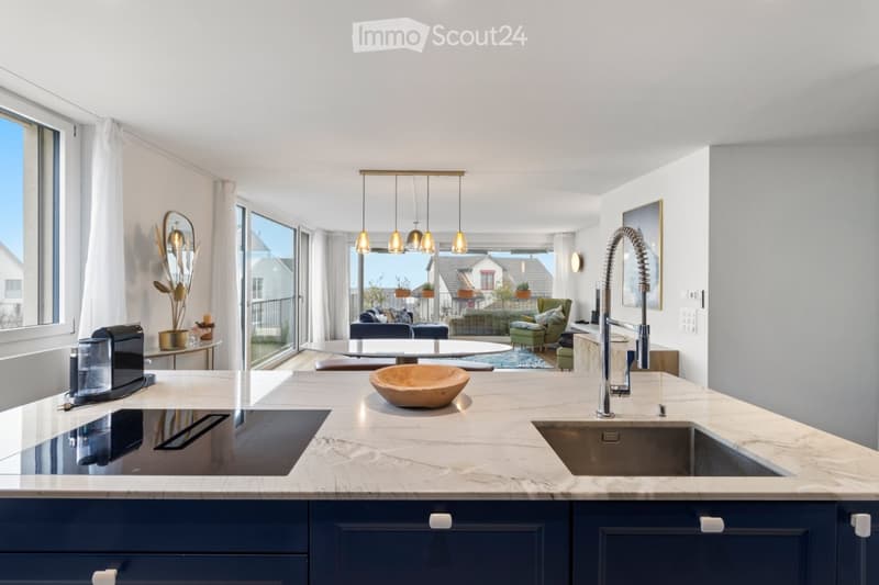 open kitchen with wooden bowl, induction stove, sink, modern faucet, marble counter, blue cabinets, large windows, balcony with railing, table, round lamp