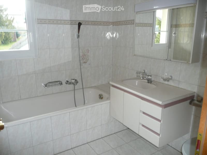 Modern bathroom with bathtub, sink, mirror, and white tiles