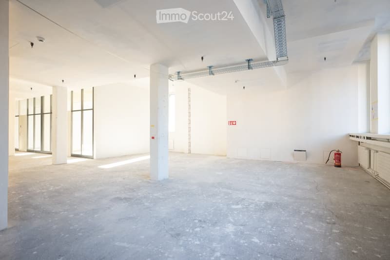 Empty room, concrete floor, glass windows, fire extinguisher.