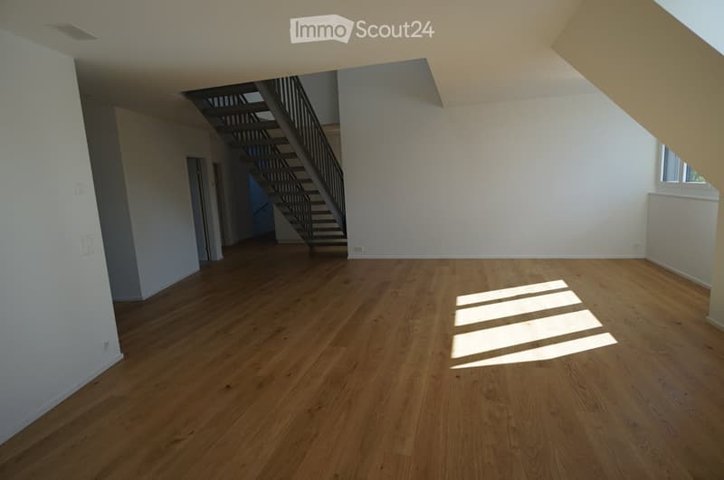 wooden floor, white walls, staircase, ceiling with beams, windows, sunlight on the floor