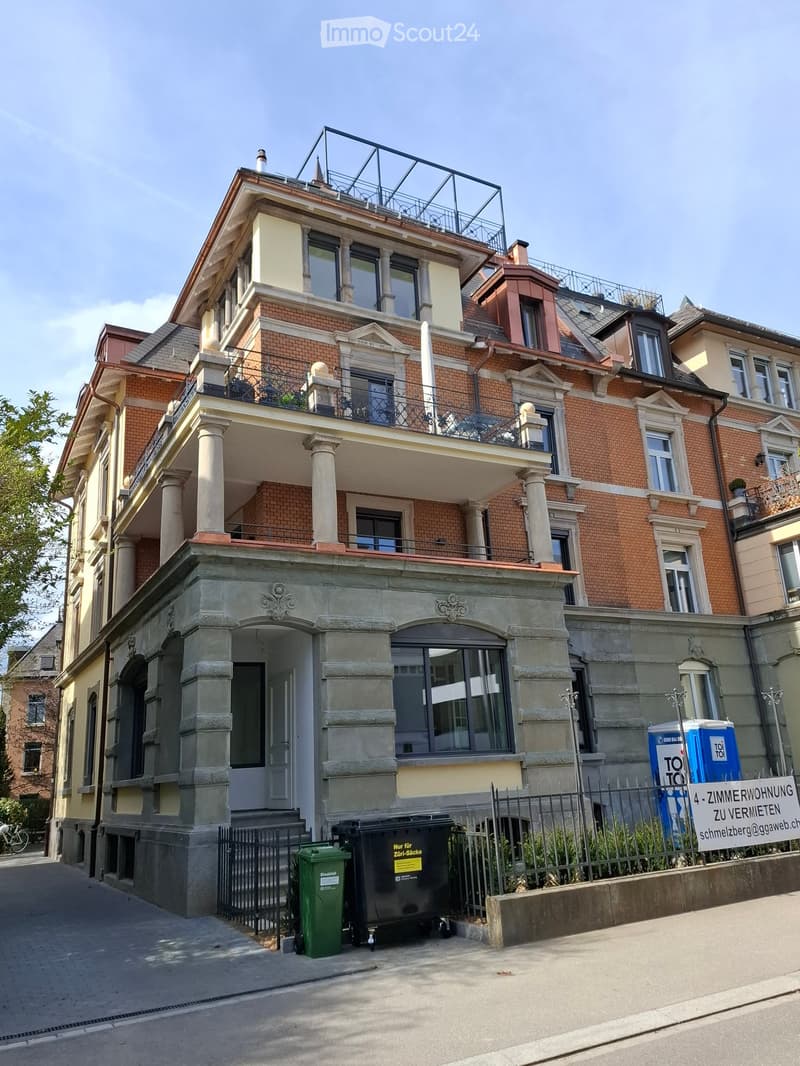 3 story building, brick facade, multiple balconies, large windows, entrance with stairs