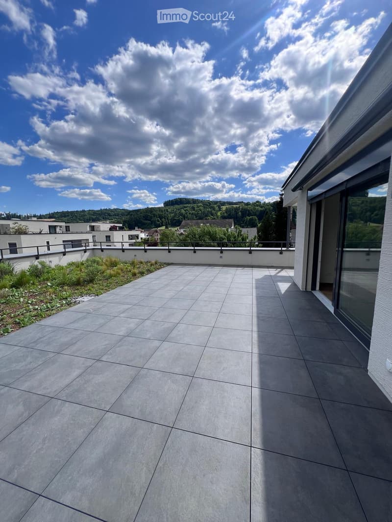 large tile terrace with railing, green plants, building views, mountain views