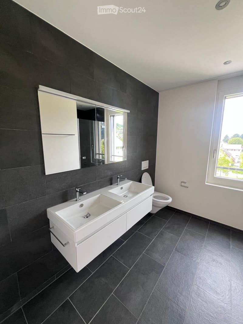 bathroom with two sinks, toilet, and a window with view