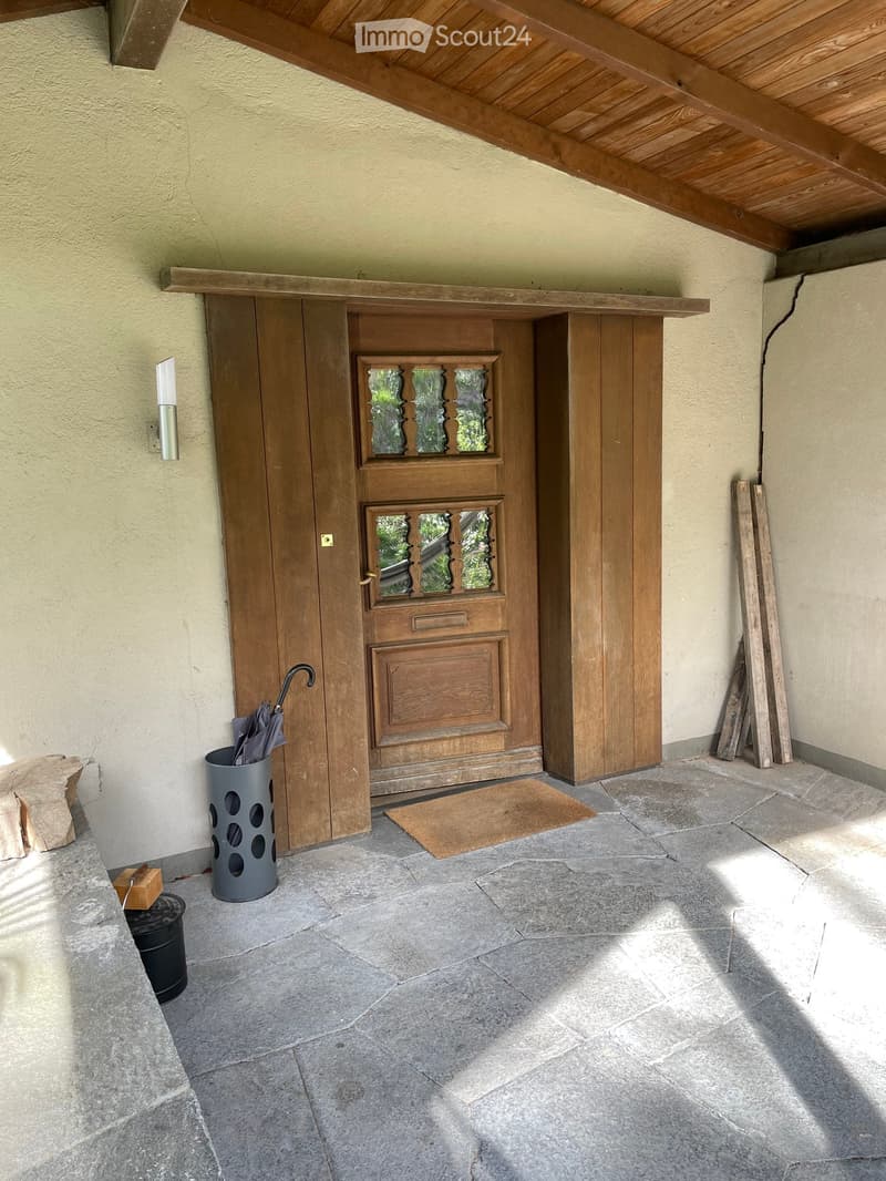 wooden entrance door, white wall, wooden ceiling, wooden floor, umbrella stand, black bucket, outdoor light