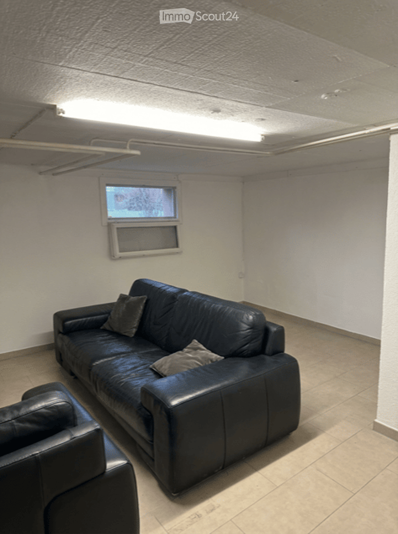 a living room with two couches, tiled floor, a small window, and a bright ceiling light