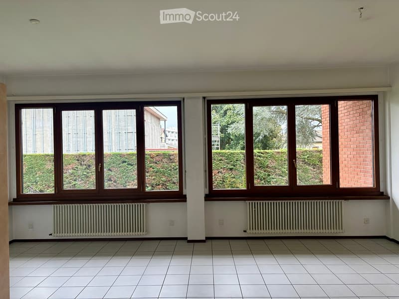 Empty room, large windows, white tiled floor, wall-mounted radiators