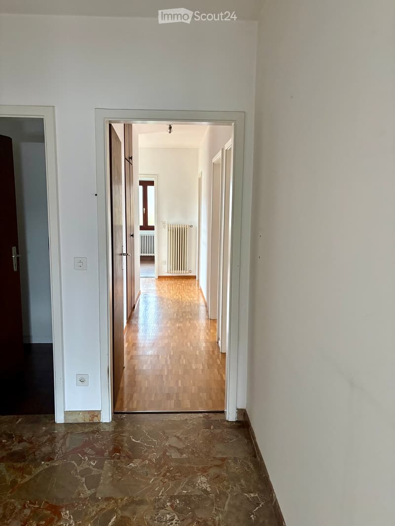 Marble floor, wooden floor in the hallway, white walls, radiators, an open door, an open window.