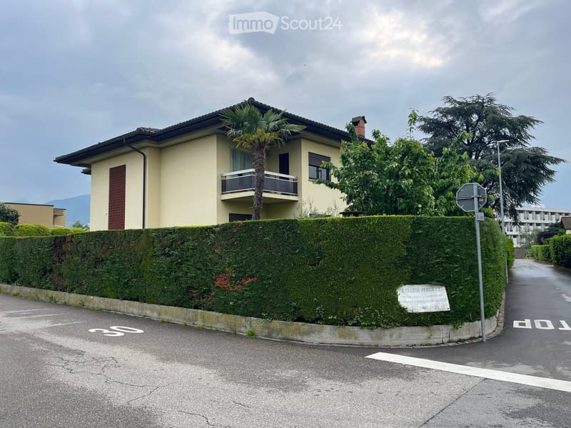 2 story house, beige, black shingles, balcony, hedge, street sign