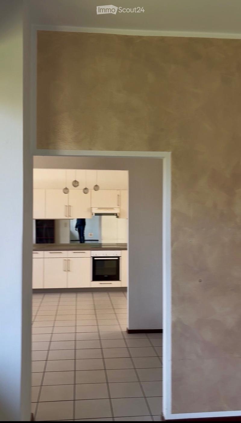 empty room, beige walls, tiled floor, white kitchen, integrated oven, large mirror