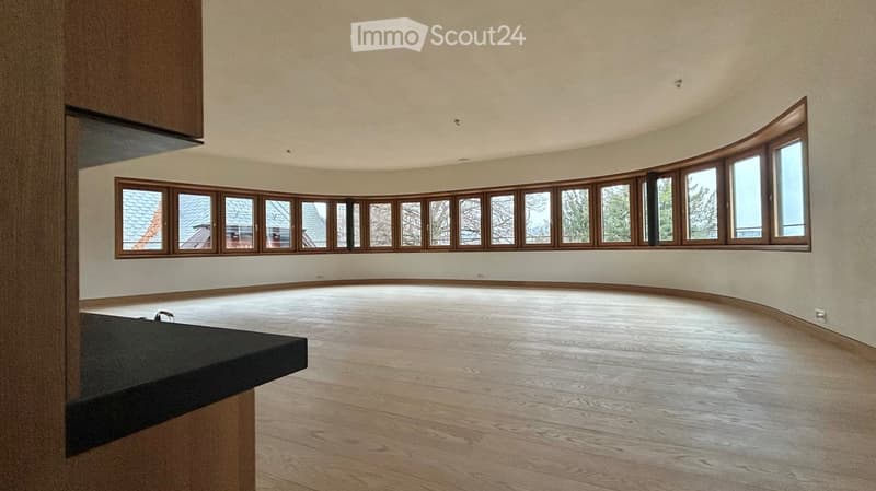 open room with many large arched windows, wooden floor