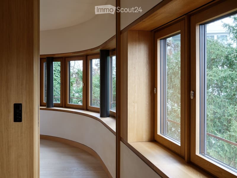 Curved hallway with wooden walls, large windows, and built-in seating areas.