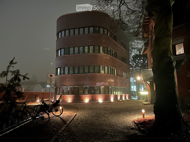 modern building with a curved facade, multiple glass windows, illuminated by exterior lights