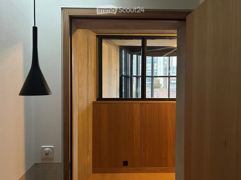 open doorway, natural light, wooden door, exposed floor beam, large window, view of the outside