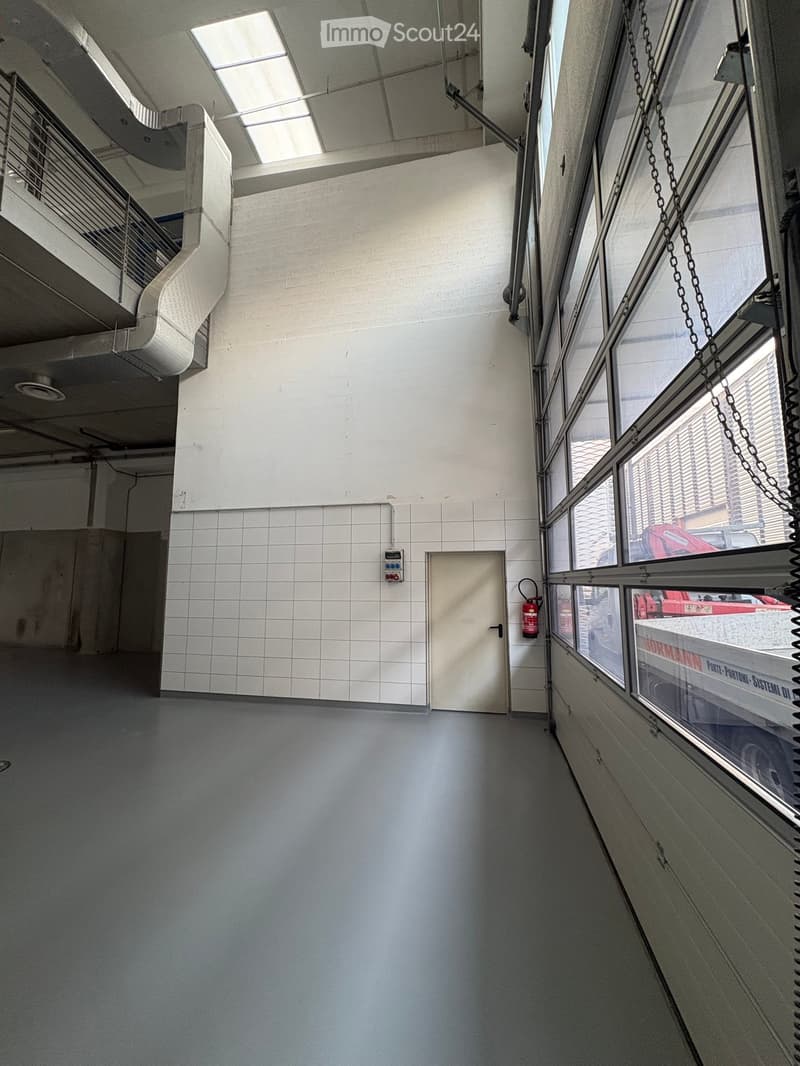 Empty room, white tiled walls, gray floor, fire extinguisher, large windows, door, balcony