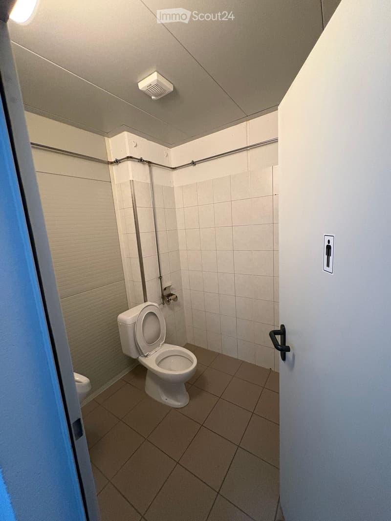 A small bathroom with a toilet, a sink, and tiled walls and floor.