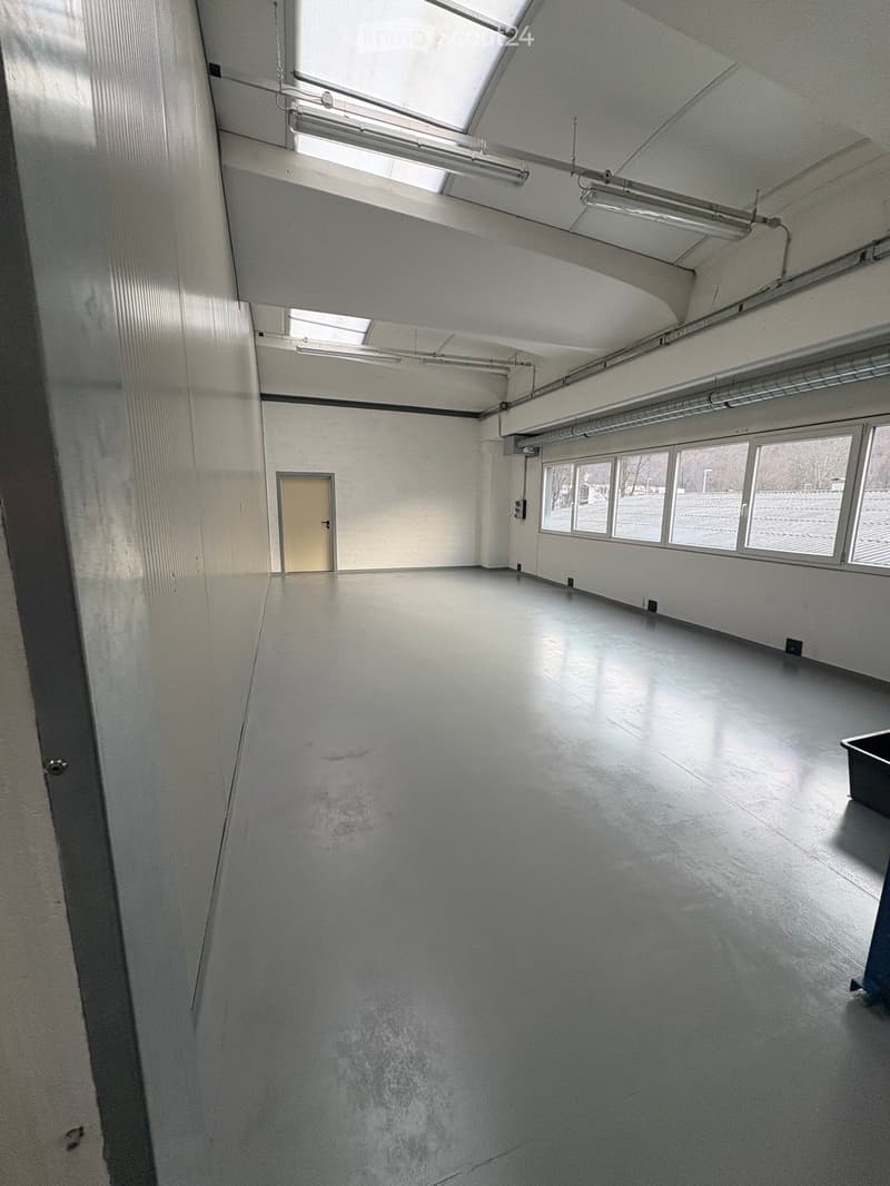 Empty room with white walls, white floor, a door, and large windows
