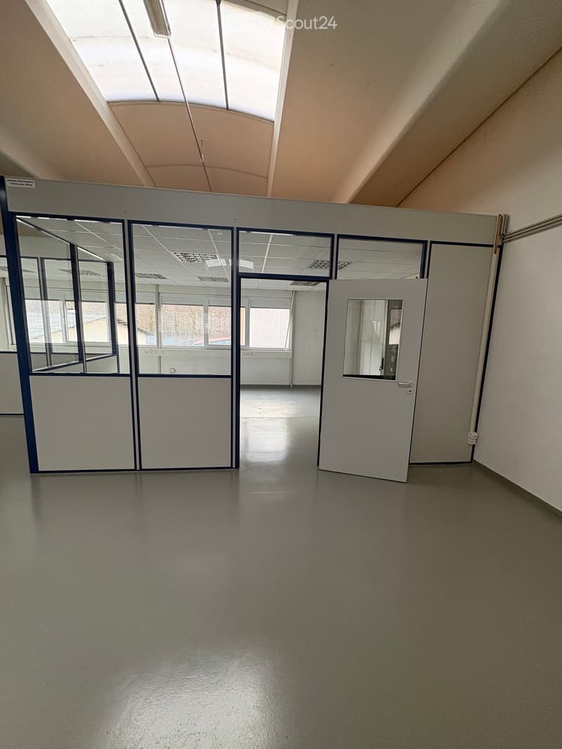 Empty room with white walls, gray floor, glass partitions, and a white door.