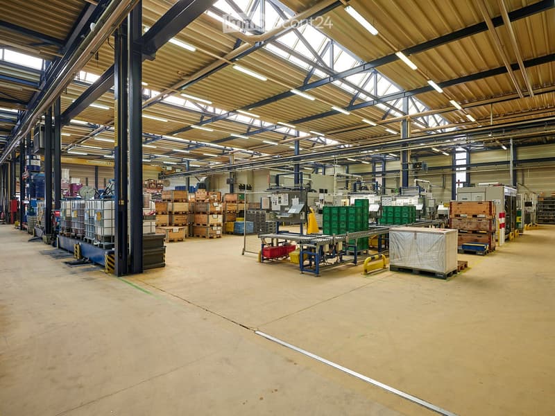 large warehouse, high ceiling, metal beams, fluorescent lights, storage boxes, pallets, machinery