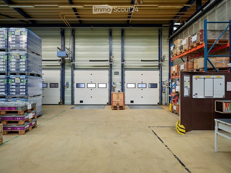 large warehouse with white doors, pallet racks, storage boxes, and shelves