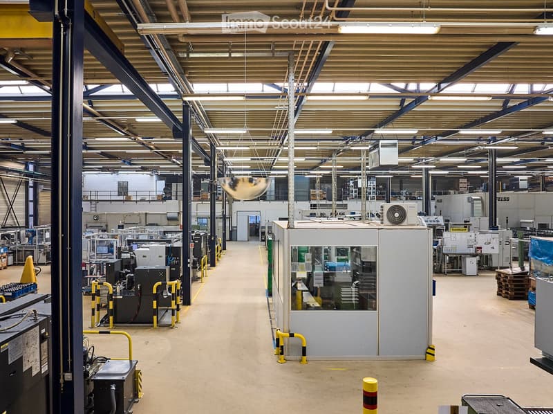 large factory with multiple machines, yellow and black poles, white walls, metal beams, fluorescent lights
