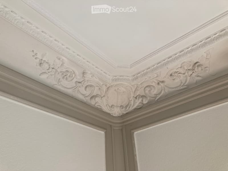 Close-up view of an ornate ceiling with intricate plasterwork and floral designs, featuring symmetrical patterns and decorative moldings.