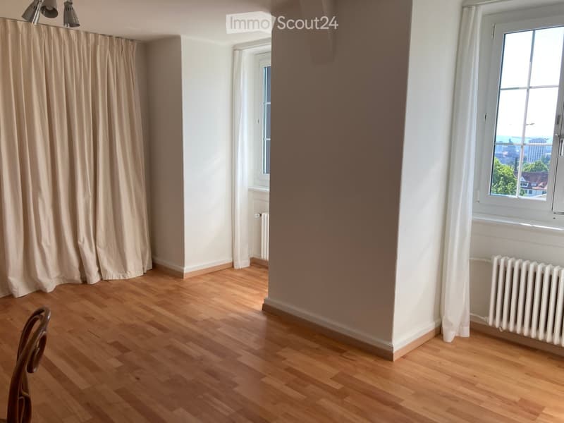Empty room with wooden flooring, white walls, large windows, and a radiator. No furniture or equipment present.